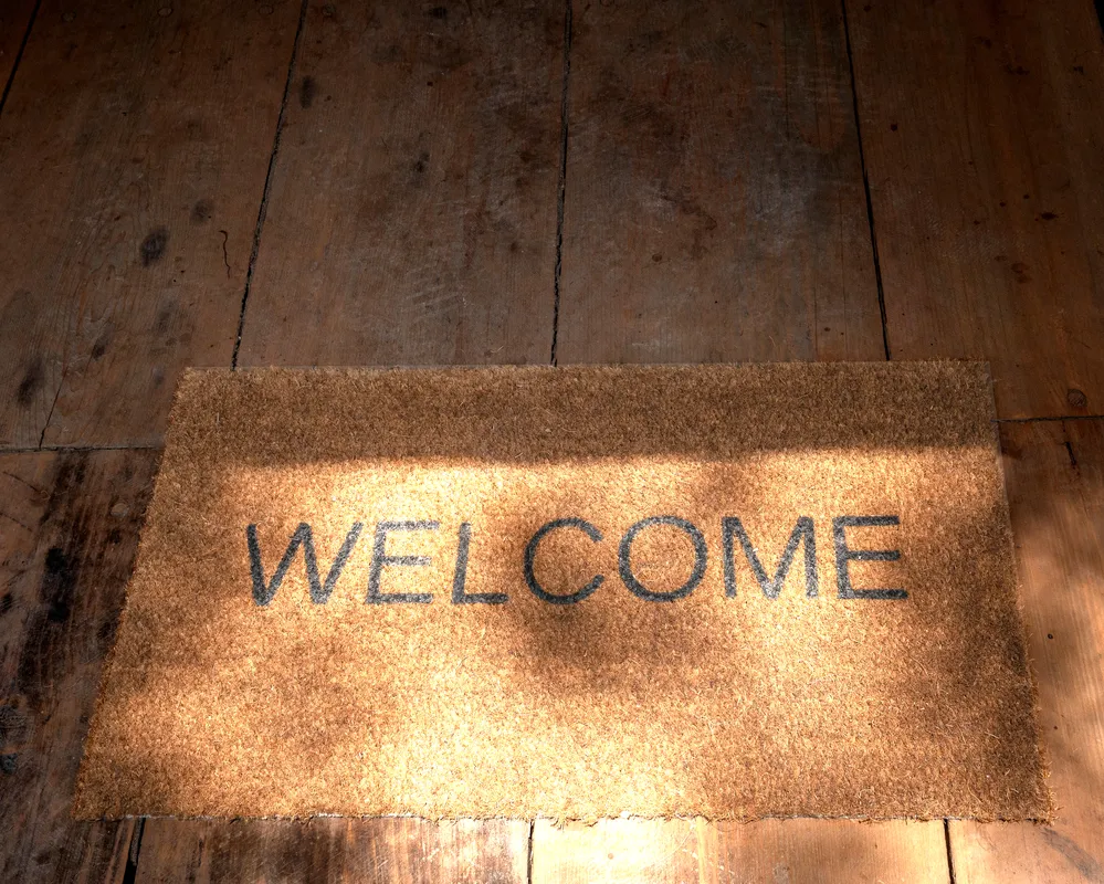 Tapete de bienvenida con la palabra “Welcome” en la entrada de la cabaña.